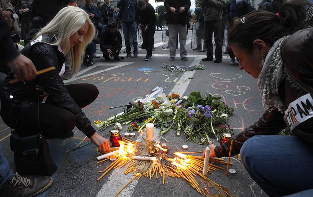 People light candles and lay flowers as police officers stand guard in front of the Government building in Skopje, Macedonia.