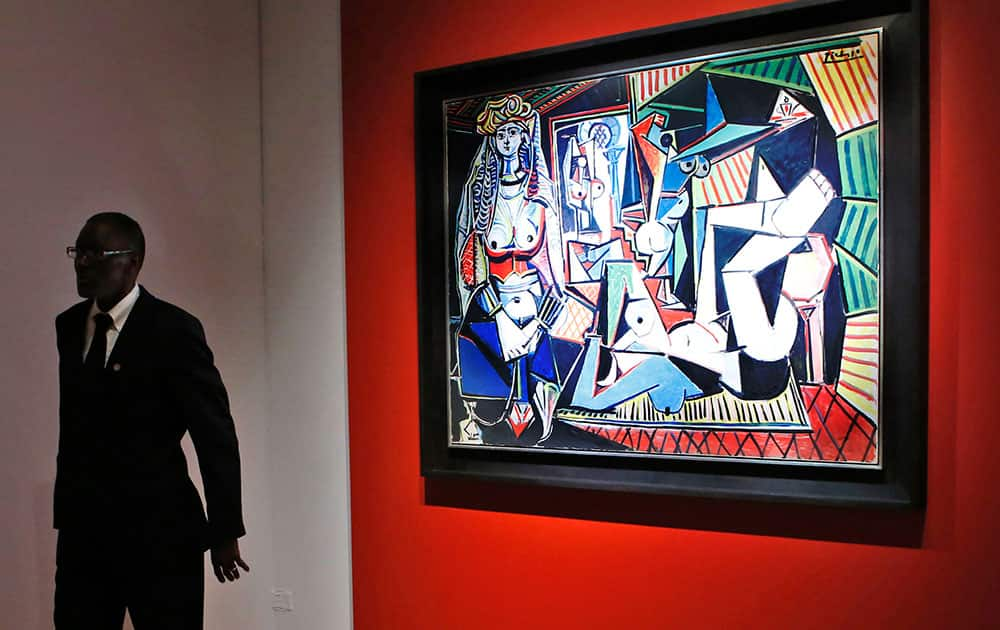 A security guard stands beside Pablo Picasso’s Women of Algiers (Version O), which sold for nearly $179.4 million, making it set a world record for artwork at auction during a sale at Christie's Rockefeller Center in New York.