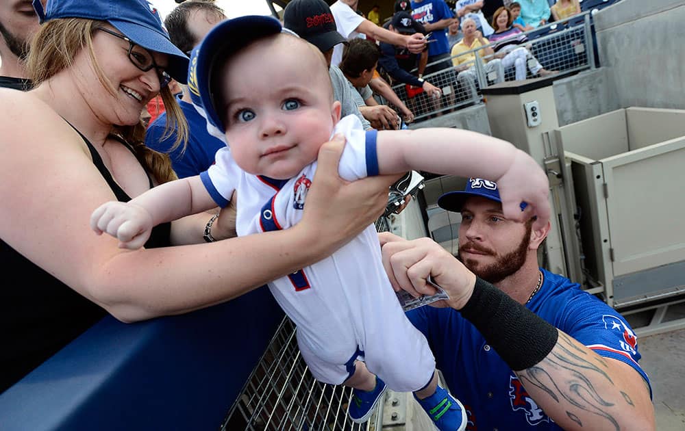 Texas Rangers' Josh Hamilton signs his autograph on the of back 6-month-old Drew Hooker as his mother Melissa holds him before a baseball game against the Nashville Sounds, in Nashville, Tenn. 