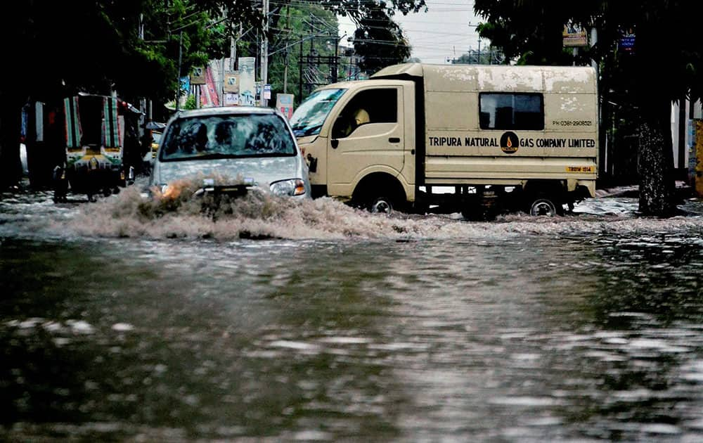 Vehicles move through a flooded street following a heavy downpour in Agartala, Tripura.
