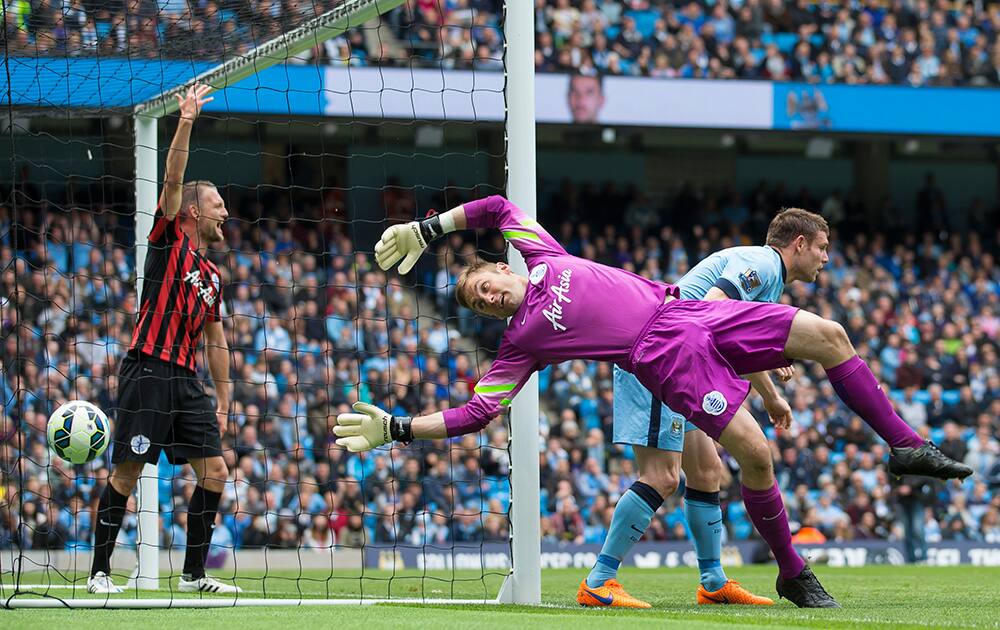 Queens Park Rangers' goalkeeper Robert Green, centre, fends away a ball after a challenge with Manchester City's James Milner, right, during the English Premier League soccer match between Manchester City and Queens Park Rangers at the Etihad Stadium, Manchester, England.