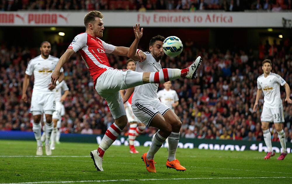 Arsenal's Aaron Ramsey, left, attempts to control the ball under pressure from Swansea City’s Angel Rangel from during their English Premier League soccer match between Arsenal and Swansea City at the Emirates stadium in London.