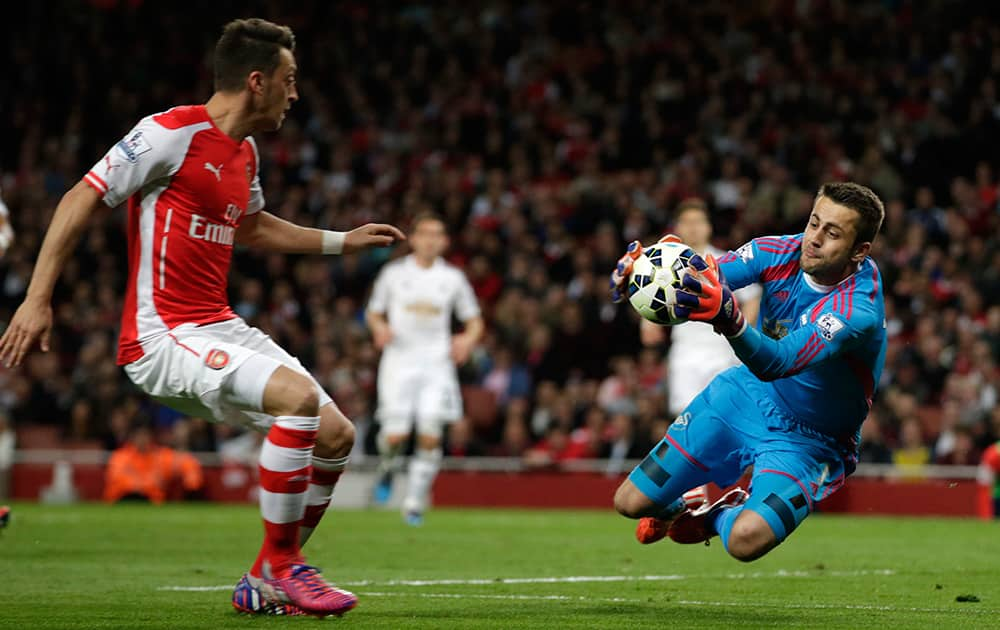 Swansea City’s goalkeeper Lukasz Fabianski collects the ball as Arsenal's Mesut Ozil advances on him during their English Premier League soccer match between Arsenal and Swansea City at the Emirates stadium in London.