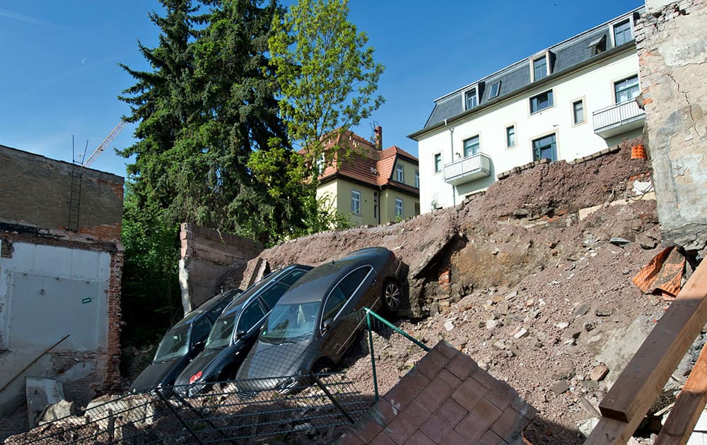 Three cars are stuck in the dirt after a parking lot slipped down a slope in Dresden, eastern Germany.