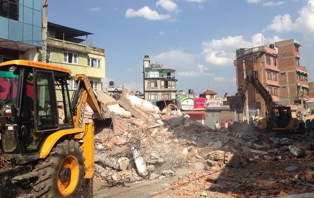 Earthmovers remove debris from a building that collapsed in an earthquake in Kathmandu, Nepal.