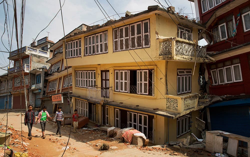 Nepalese children walk past quake damaged houses in Chautara, Nepal.