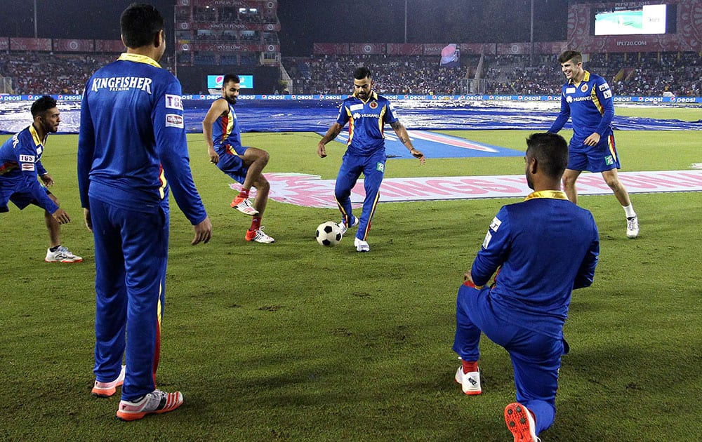 Royal Challengers Bangalore captain Virat Kohli plays one bounce with his team mates as rain delays the start of an IPL 8 match against Kings XI Punjab in Mohali.