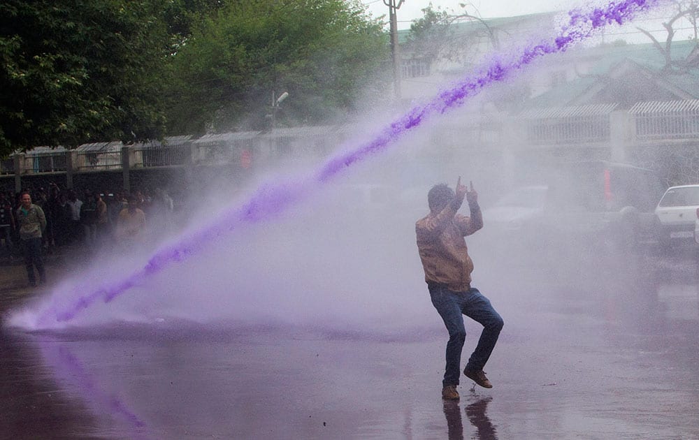 Police use colored water from a water canon to disperse Kashmiri government employees in protest in Srinagar, India.