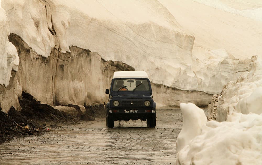 A vehicle drives past walls of snow on the Zojila Pass road, about 110 kilometers (68 miles) north of Srinagar, India.