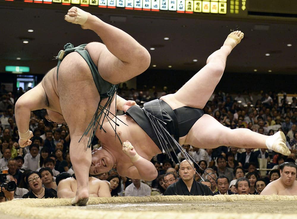 Sumo wrestler Takayasu, left, throws opponent Ikioi to win their bout on the fifth day of the Summer Grand Sumo Tournament at Ryogoku Kokugikan sumo arena in Tokyo.