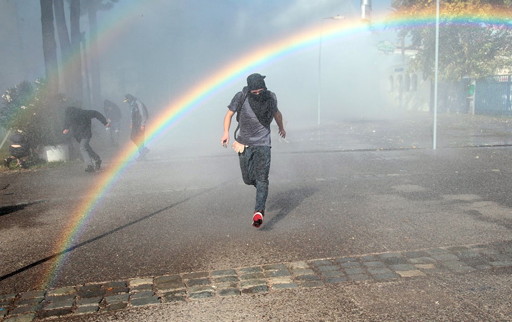 A protester runs from a jet of water shot from a police water cannon in the courtyard of the University of Santiago, during clashes between students and police, in Santiago