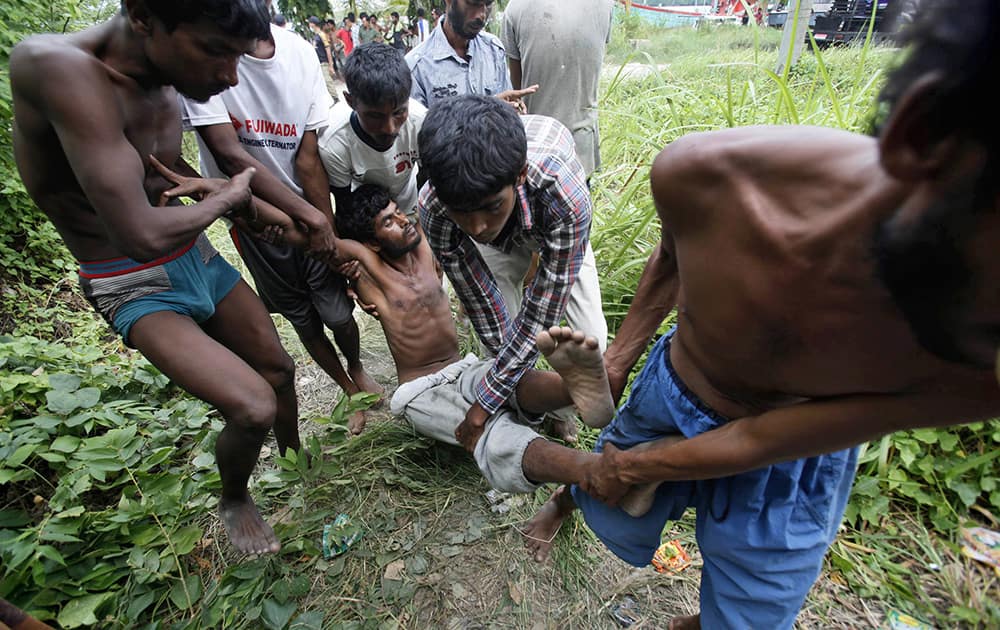 Bangladeshi migrants carry a sick friend toward a temporary shelter upon arrival at Kuala Langsa Port in Langsa, Aceh province, Indonesia.