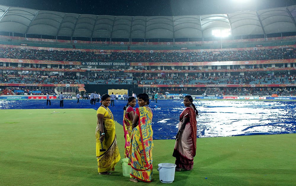 Ground staff wait for the rain to ease during IPL 8 match between Sunrisers Hyderabad and Royal Challengers Bangalore in Hyderabad.