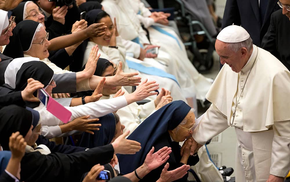 A nun kisses the hand of Pope Francis as others reach out for the pontiff, during an audience with clergy of Roman archdiocese, in the Paul VI hall at the Vatican