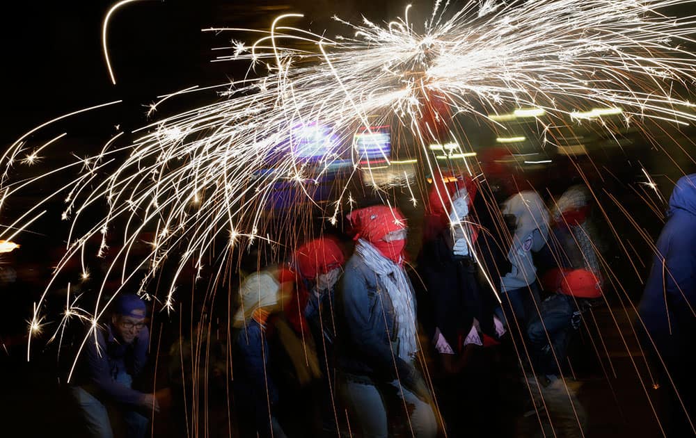 Revelers hold their fireworks as they take part in a 