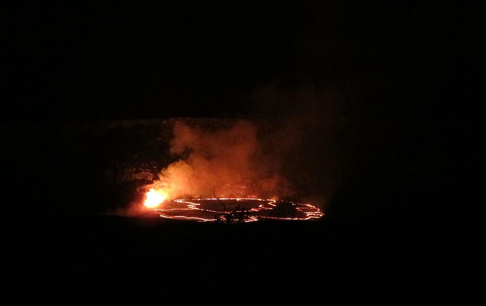 In this Saturday, May 9, 2015 photo, molten rock lights up the night as it spews into a lake of lava near the summit of Kilauea volcano on Hawaii's Big Island.