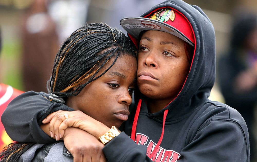 LaToya Howell of Waukegan, right, hugs her 12-year-old daughter Jayla as people, in Waukegan, Ill., protest the decision by Lake County State's Attorney Michael Nerheim not to file charges in the April police shooting of Howell's son Justus in nearby Zion.