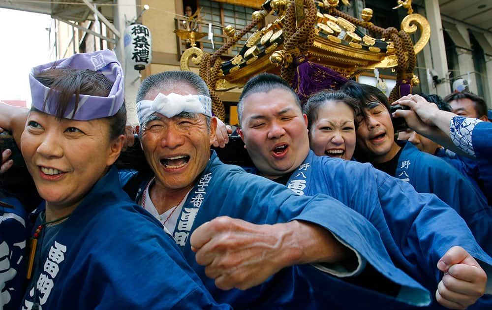 Participants clad in traditional happi coats carry a mikoshi, or portable shrine in the annual Sanja Festival parade through a street of Tokyo's Asakusa shopping district.