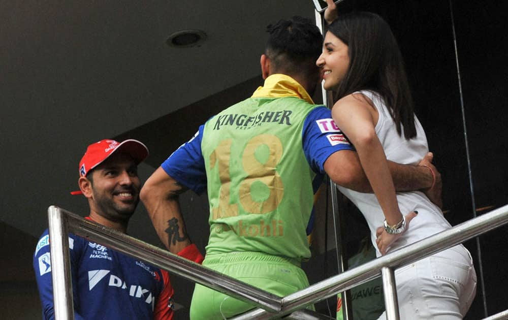 RCB Skipper Virat Kohli talks with his girlfriend Bollywood actor Anushka Sharma as cricketer Yuvraj Singh looks on while Royal Challengers Bangalore and Delhi Daredevils IPL match stopped due to rain in Bengaluru.