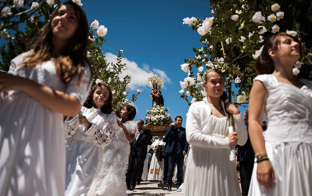 Teenagers dressed in bridal white surrounded by flowers, take part in the pilgrimage 