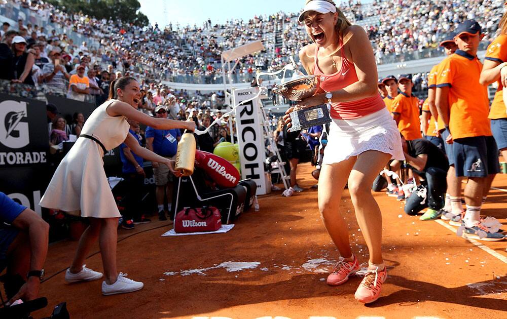 Maria Sharapova, of Russia, is sprayed with champagne as she holds the trophy after defeating Carla Suarez Navarro of Spain.