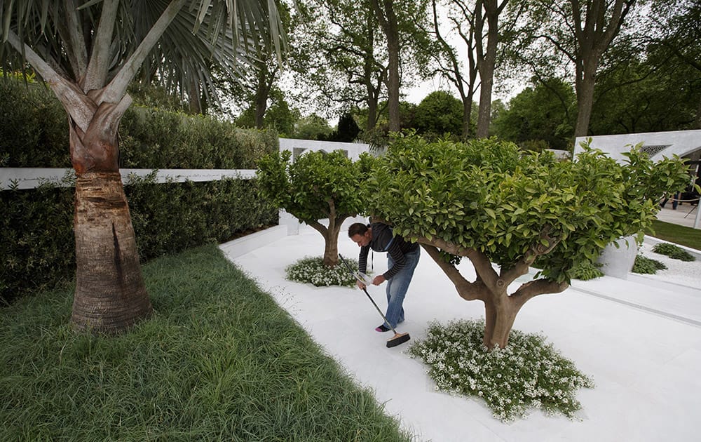 A person brushes the floor in the garden display entitled The Beauty of Islam by Al Barari, at the Chelsea Flower Show in London.