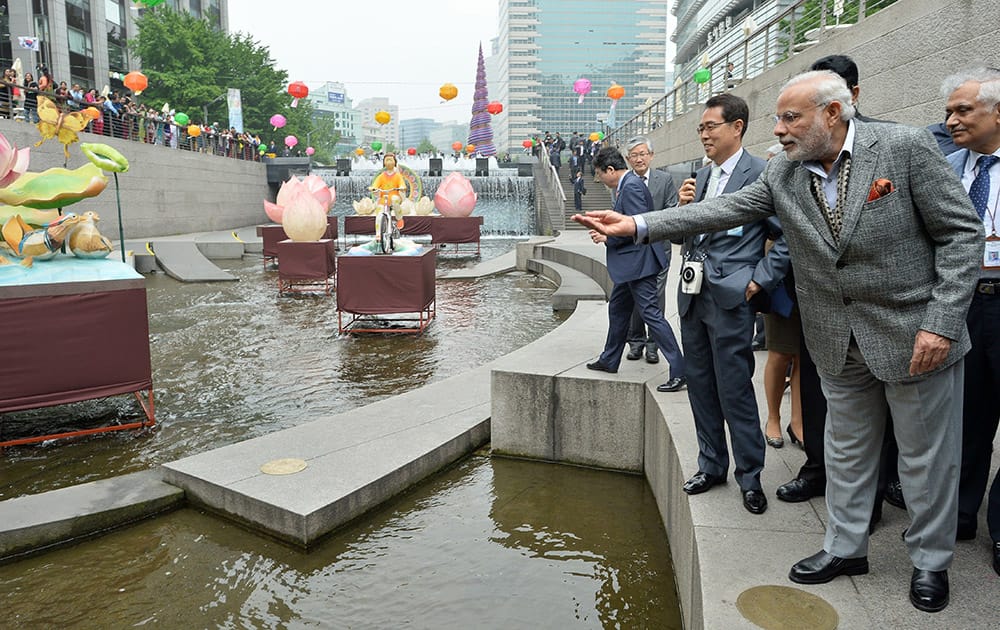 Prime Minister Narendra Modi, tosses a con into the Cheonggye stream in Seoul, South Korea.