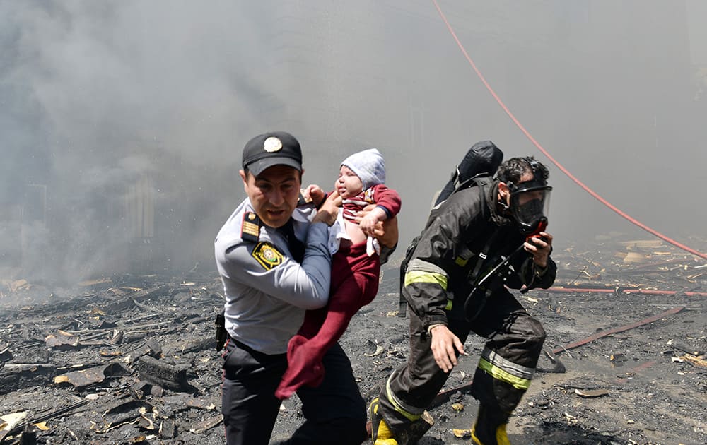 A police officer and a fire fighter help child victim of an apartment building fire in Baku, Azerbaijan.