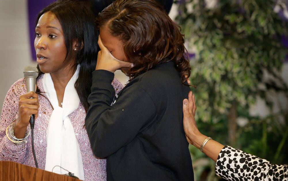 West Side Academy senior A'Ja Booth, right, reacts next to her teacher Nadirah Muhammad during a welcome rally for Booth at the school in Detroit. 