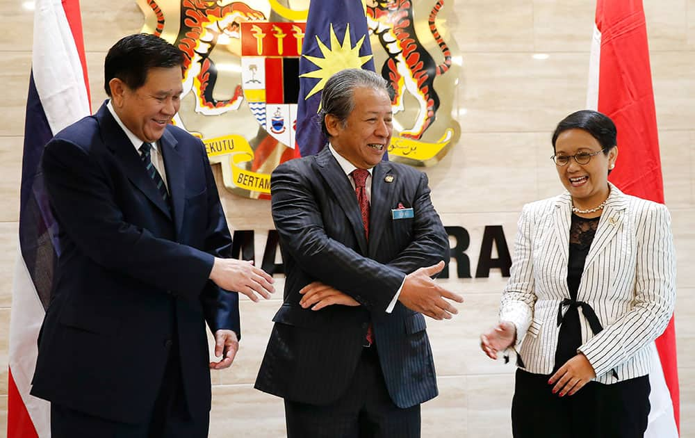 Malaysia's Foreign Minister Anifah Aman, center, shakes hand with Thailand's Minister of Foreign Affairs Tanasak Patimapragorn, left, and Indonesia's Minister of Foreign Affairs Retno Marsudi during an emergency meeting called to discuss how to solve the migrant problem at ministry of Foreign Affairs in Putrajaya Malaysia.