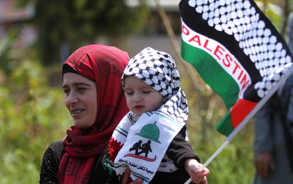 A Palestinian woman who lives in Lebanon carries her child with the Palestinian flag during a protest marking the 67th anniversary of Nakba, or Catastrophe, in front of the United Nations peacekeepers (UNIFIL) headquarters in the costal town of Naqoura, southern Lebanon.