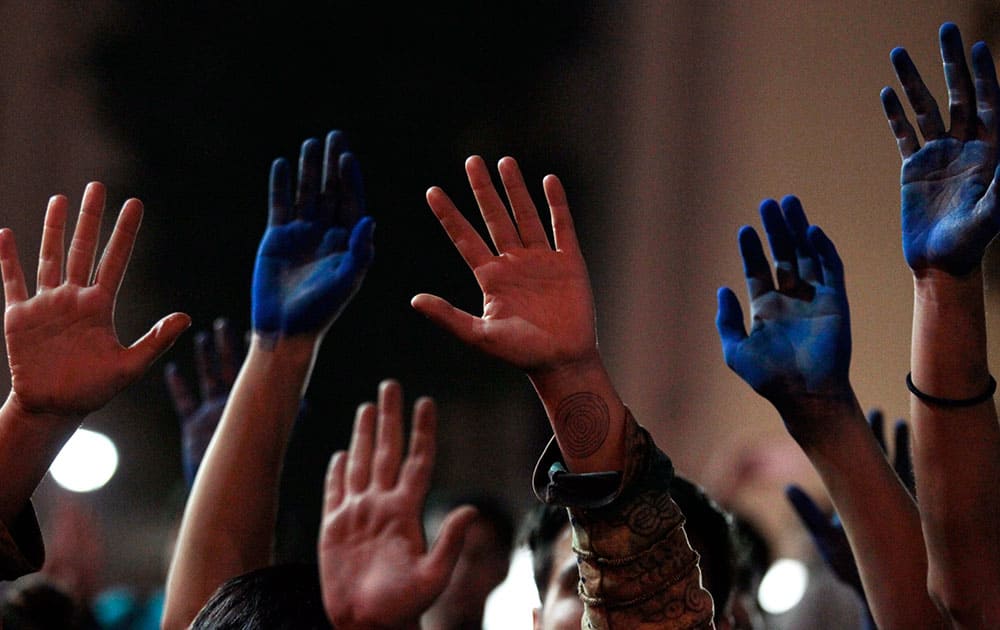 A group of protesters hold up their hands, some colored blue, during a march in Santiago, Chile.