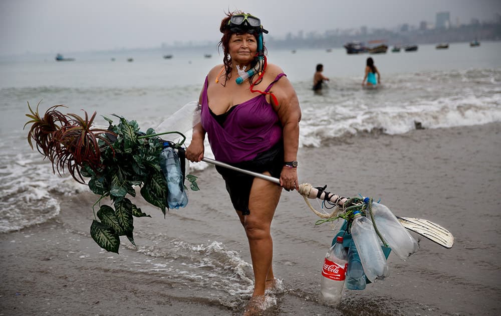 Graciela Meneses poses for a picture on Fishermen's Beach, holding her self-made float, decorated with fake, plastic plants, after swimming in the Pacific Ocean in Lima, Peru. 