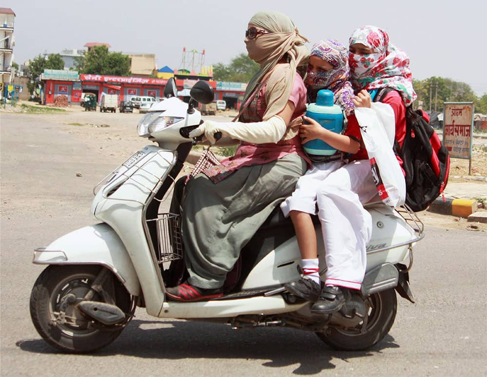 A woman and two girls cover themselves for protection from heat on a hot day.