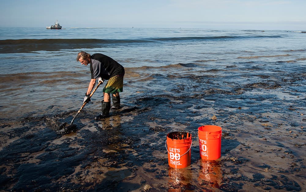 A man shovels up oil on a section of beach about a mile east of Refugio State Beach, Calif.