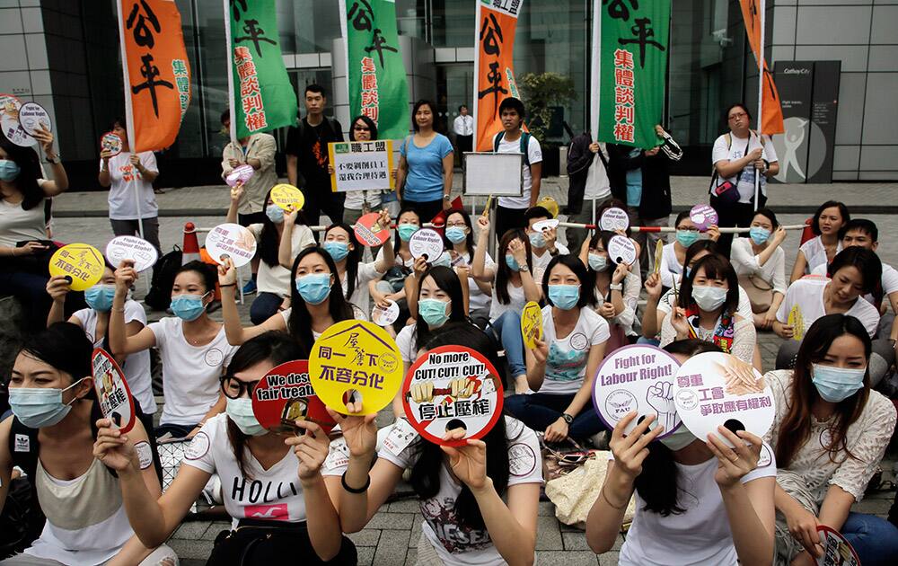 Hundreds of Cathay Pacific flight attendants raise placards outside the Hong Kong airline’s headquarters as they hold a protest over some pay increases and cabin crew meal allowances in Hong Kong.