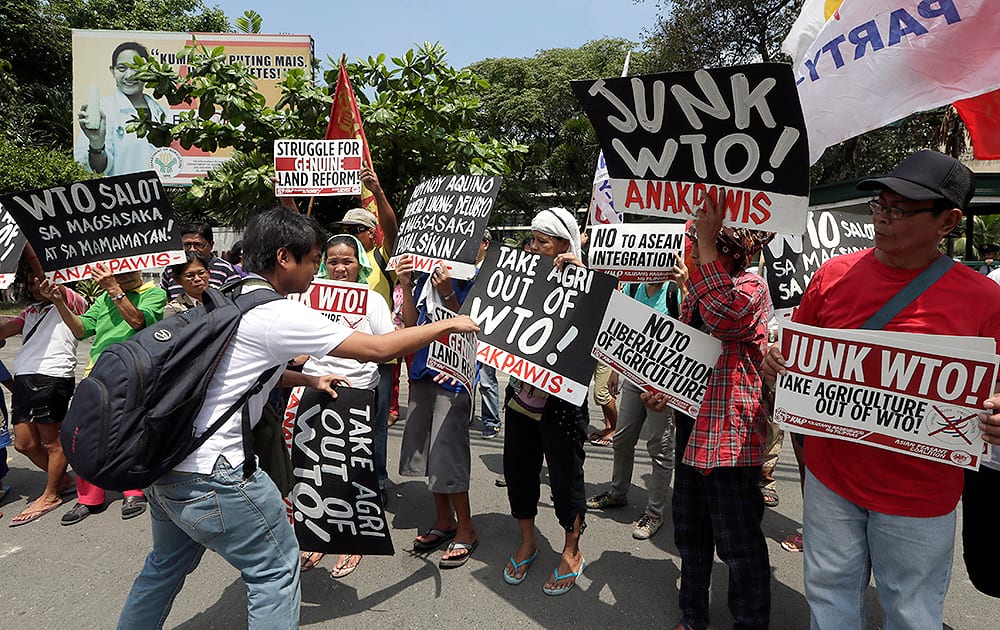 Protesters display placards during a rally at the Department of Agriculture to coincide with the visit in the country of Roberto Azevedo, Director General of the World Trade Organization (WTO), at suburban Quezon city, northeast of Manila.