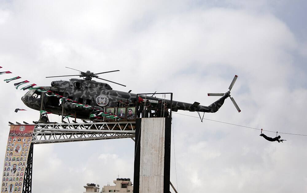 A Palestinian Hamas security officer slides on a wire, connected to the wreckage of late Palestinian President Yasser Arafat's helicopter, installed on a structure, during a police academy graduation ceremony in Gaza City.