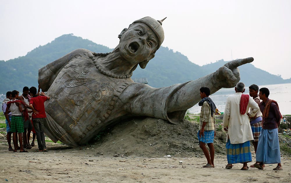 People stand near a part of a bronze statue of Lachit Borphukan, an army general from the northeastern state of Assam, set to be installed in the middle of the Brahmaputra on a podium, in Guwahati.