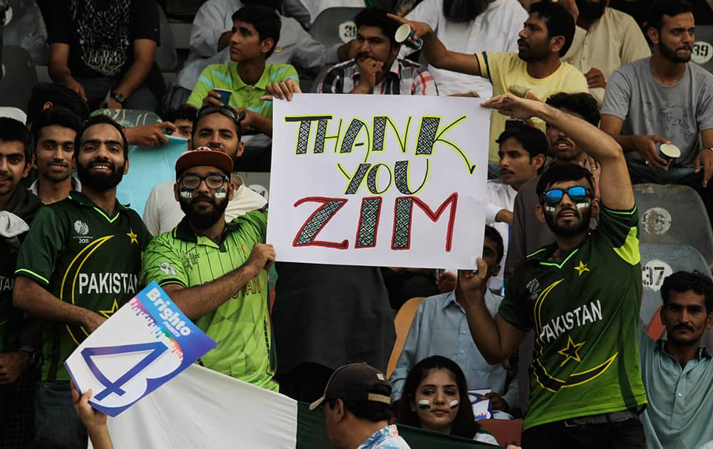 Pakistan's cricket fans hold up a poster to welcome the Zimbabwe cricket team at the Gaddafi stadium in Lahore, Pakistan.