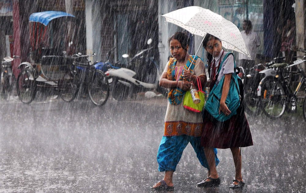 Young girls shelter under an umbrella during heavy rains in Agartala.