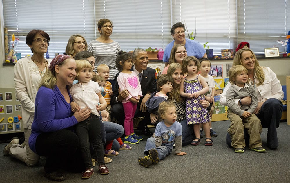 President Barack Obama poses for group photos during his visit to a child development center at Adas Israel Congregation in Washington.