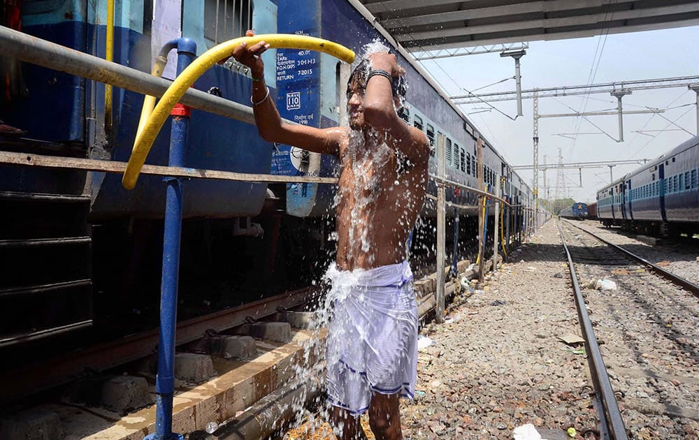 A man takes bath under a train water supplying pipe at a railway station in Allahabad. Most of north India has been reeling under heat wave conditions with temperature soaring to over 46 degree Celsius. 