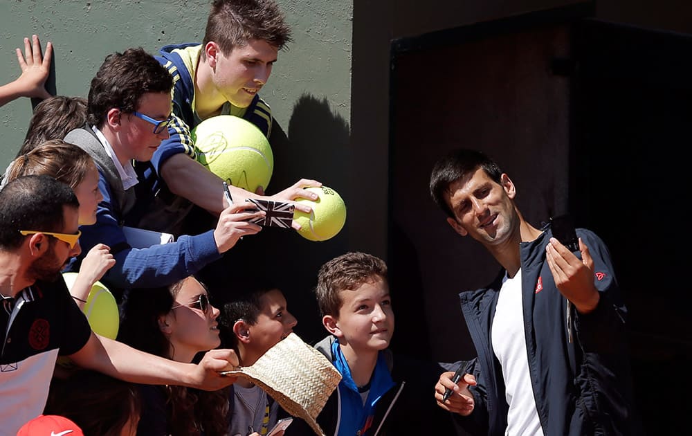 Serbia's Novak Djokovic takes a selfie with fans after a training session for the French Tennis Open at the Roland Garros stadium, in Paris.