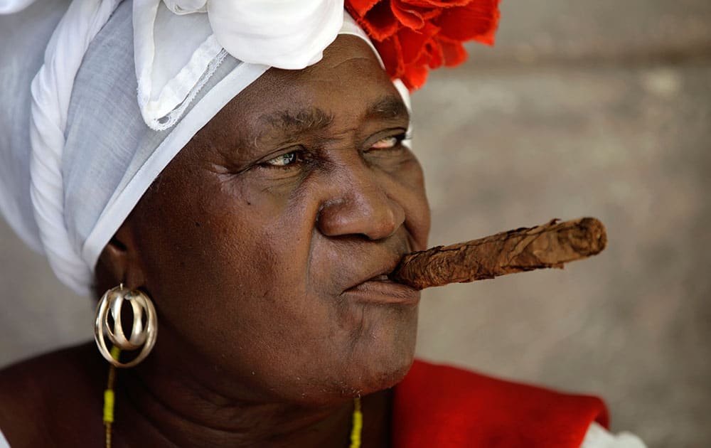 Street entertainer and fortune teller ¨Juana La Cubana¨ holds a cigar in her mouth as she waits for tourists in Havana, Cuba.