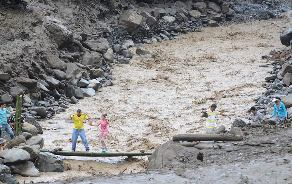 Residents cross an overflowing ravine in Colombias northwestern state of Antioquia, where a deadly flood and mudslide swept through a day earlier.