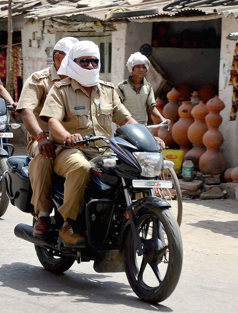 Policemen cover their faces to protect themselves from scorching heat on a hot day in Mirzapur.