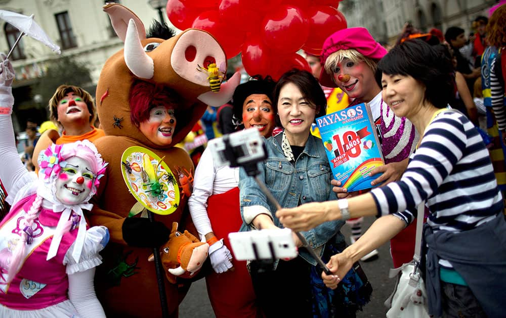 Tourist Gina Youginkim, right, and Margaret Kahng, from South Korea, third from right, pose for a picture with clowns during a march commemorating the Peruvian clown day in Lima Peru.