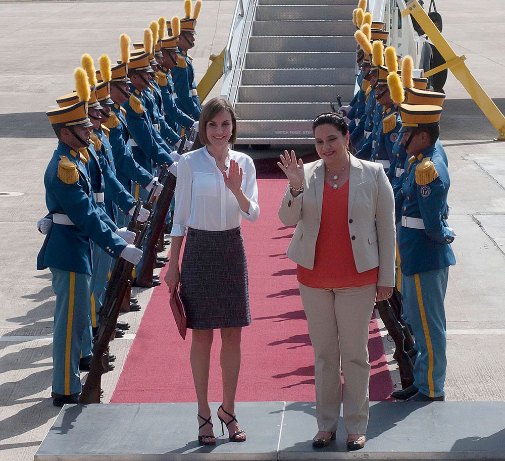 Queen Letizia of Spain, center left, and Honduras' first lady Ana Garcia wave to the press after the Queen arrived at the Palmerola air base near Comayagua, Honduras.