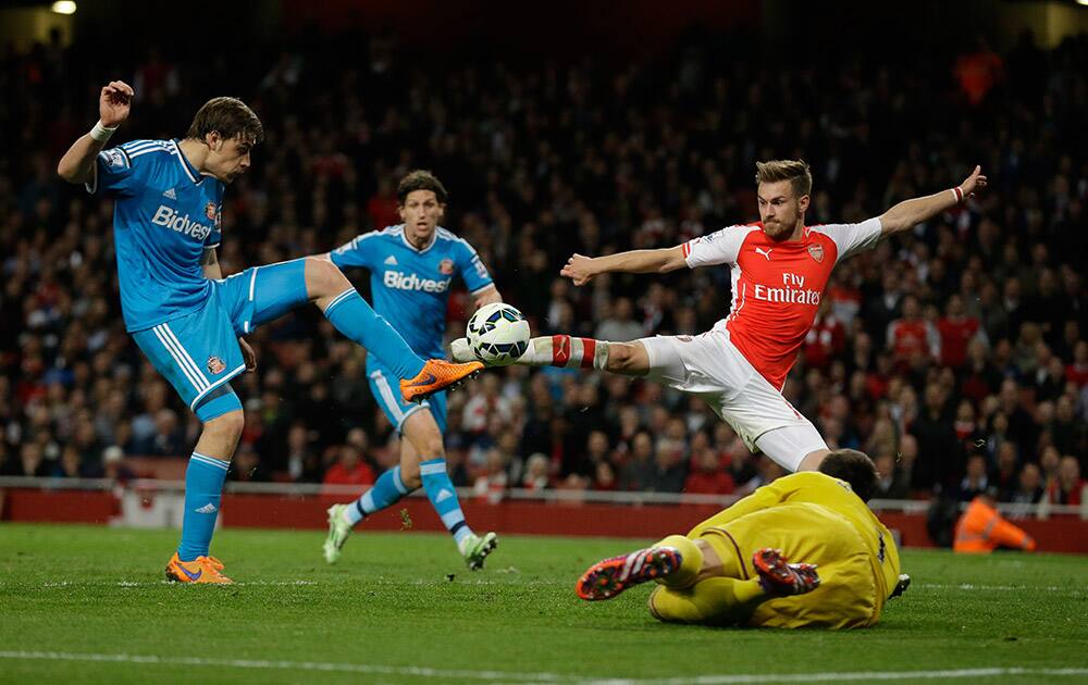 Arsenal's Aaron Ramsey, top right, attempts to score a rebound off a Theo Walcott shot beside Sunderland's Sebastian Coates, left, and goalkeeper Costel Pantilimon, bottom right, during the English Premier League soccer match between Arsenal and Sunderland at the Emirates Stadium in London.